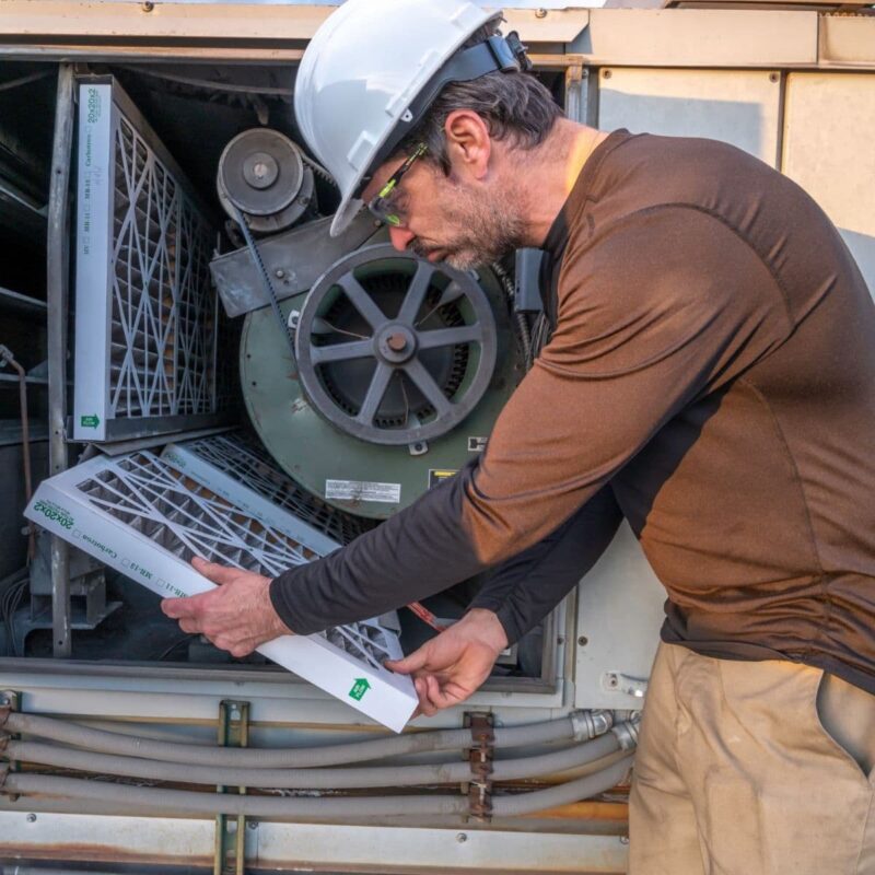 man in a brown shirt inspecting air filters during a heater replacement